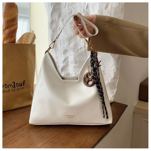 Detail of white leather hobo bag with brown knot charm and striped woven rope decoration