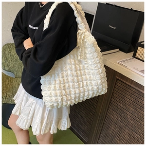 Close-up of white bubble texture tote bag with lace shoulder strap and bow detail