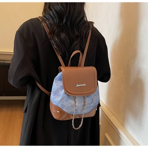 Detailed back view of a small brown and blue patchwork cat print backpack with metal chains