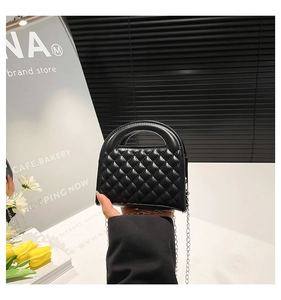 Close-up of black quilted PU leather mini handbag with silver chain and curved handle