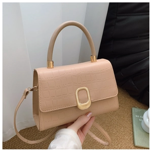 Detail of apricot crocodile embossed leather handbag with gold wavy buckle and handle