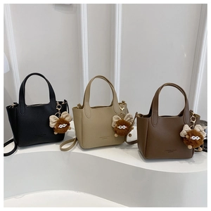 Three bucket bags in black beige and brown with cute plush monster charms on display