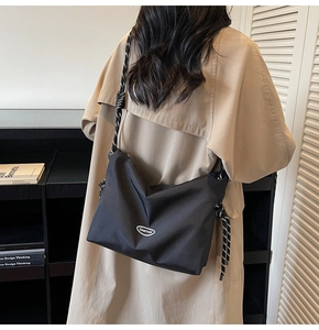 Detail of minimalist black nylon crossbody bag with stylish black and white rope strap