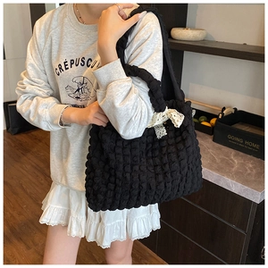 Detail view of black bubble textured tote bag featuring a white lace bow accent