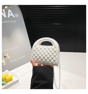 Close-up of white quilted mini bag with glossy finish and detachable metal chain strap