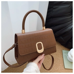 Detail of brown crocodile pattern baguette bag featuring elegant gold oval twist lock