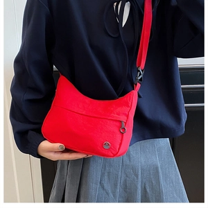 Detail of red waterproof nylon crossbody bag with metallic M logo and adjustable strap