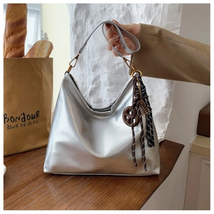 Detail of silver metallic hobo bag with braided tassel charm and fashion lettering