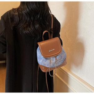 Detail of blue denim and brown leather mini backpack with metal chain and cat prints
