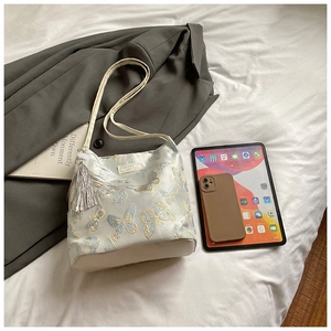 Detail of white jacquard tote with gold butterfly pattern and elegant tassel charm