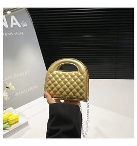 Detailed macro view of the gold quilted texture and metal chain strap on this mini handbag