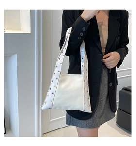 Sac fourre-tout blanc chic avec œillets métalliques porté par un mannequin en style minimal
