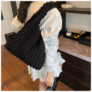 Close-up of black puffy bubble texture shoulder bag with textured wide strap design