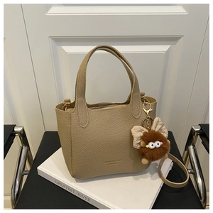 Détail du sac seau en cuir grainé kaki avec lettrage mode et breloque peluche