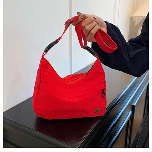 Detail of red nylon crossbody bag showing the adjustable strap and round metal logo