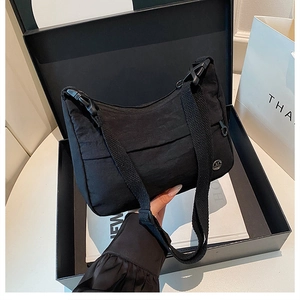 Detail of a black crescent nylon crossbody bag with adjustable strap and metal M logo