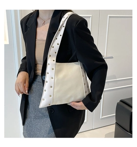 Détail latéral d'un sac à bandoulière en cuir blanc avec œillets dorés et large sangle
