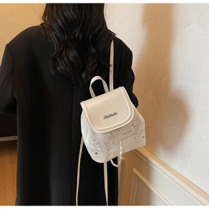 Close-up of white mini backpack with metal logo and cute cat prints on black coat
