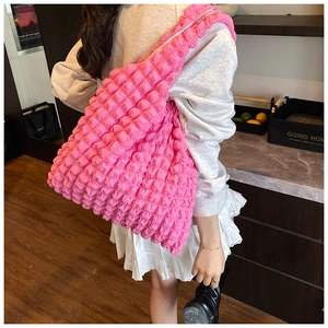 Detailed close-up of hot pink popcorn texture tote bag worn on shoulder in indoor setting
