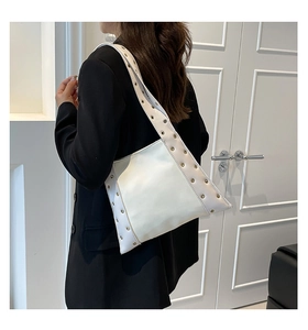 Détail du sac cabas en cuir verni blanc avec œillets métalliques dorés sur la bandoulière