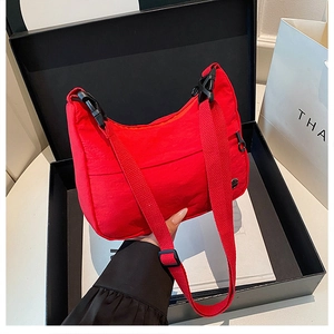 Close-up of red waterproof nylon crossbody bag featuring black buckle and adjustable strap