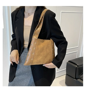 Gros plan d'un sac porté épaule marron rétro avec œillets argentés et texture mate douce
