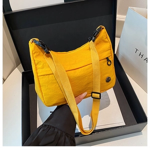 Close-up of vibrant yellow nylon crossbody bag featuring a metal logo and buckle detail