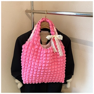 Detail of rose pink waffle fabric tote bag with a white lace bow hanging on a blazer