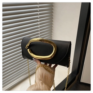 Detailed shot of black leather handbag with oversized gold metal hardware and chain