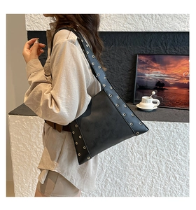 Détail du sac hobo trapèze noir avec des œillets métalliques dorés sur la bandoulière