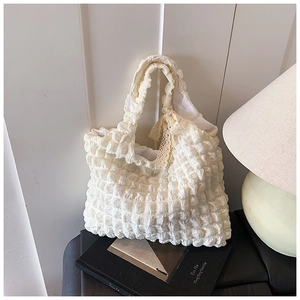 Detail of cream white pleated tote bag featuring cloud texture and a lace bow accent