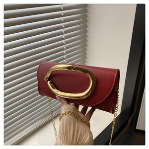 Detail of red leather crossbody bag with oversized gold oval buckle and chain strap