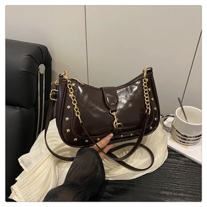 Detail view of coffee leather shoulder bag with gold rivets and metallic clasp closure