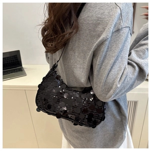 Detail view of black sequin baguette bag on model showcasing stylish fit and texture