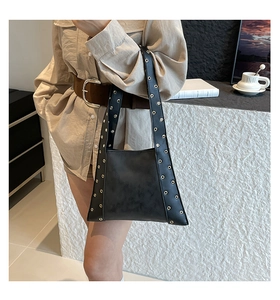 Sac sous le bras en cuir noir avec rivets argentés porté à l'épaule par un mannequin