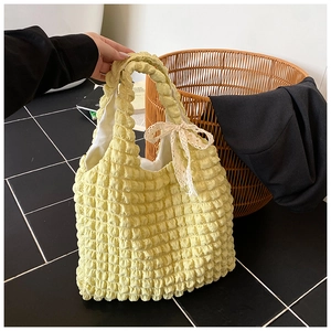 Close-up of a yellow puffy tote bag with pleated fabric and a lace bow decoration