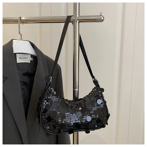 Close-up of black crescent sequin bag with silver zipper hanging on a metallic rack