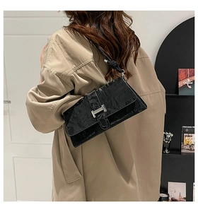 Detail of the elegant black PU leather shoulder bag with a metallic H-buckle closure
