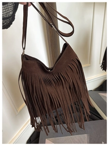Detail van bruine suède hobo-tas met dichte bohemian franjes en een metalen magneetsluiting