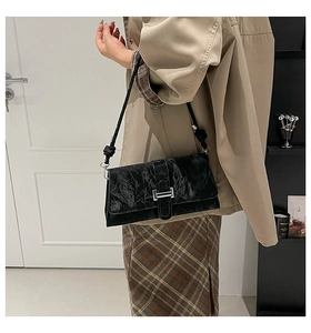 Detail shot of black wrinkled texture shoulder bag with elegant silver metallic buckle