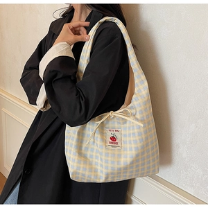 Dettaglio borsa in tela a quadretti gialli e blu con coulisse laterale e patch logo retrò