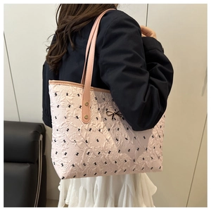 Close-up of pink textured tote bag with black bow patterns and metal rivet handle detail