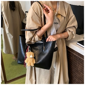 Chic black faux leather tote bag with fashion tag and cute plush bear charm detail
