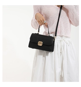 Detalle de bolso cuadrado vintage de piel negra con hebilla dorada en un modelo