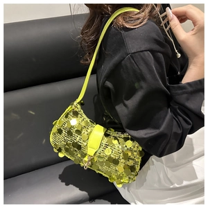 Détail d'un sac à bandoulière en sequins vert fluo porté sur une tenue noire élégante