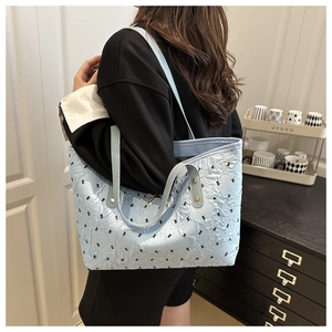 Close-up of light blue quilted tote bag with black bow patterns and metal buckle