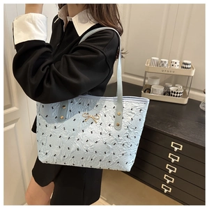 Detail showing pleated texture and golden bow hardware on a light blue tote bag