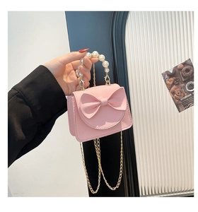 Detail of pink mini quilted bag featuring a decorative bow and elegant pearl top handle