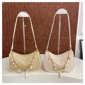 Detail of straw woven underarm bags with pearl and seashell charm chain straps