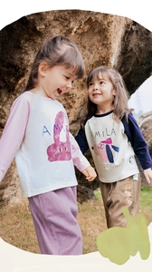 Outdoor shot of two toddlers wearing colorful patchwork raglan sleeve cartoon t-shirts